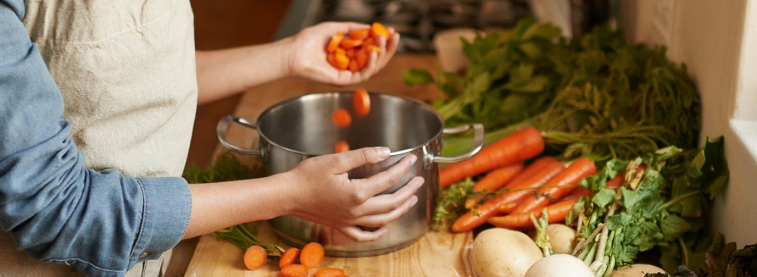 Cropped shot of a woman cutting carrots on a cutting board
